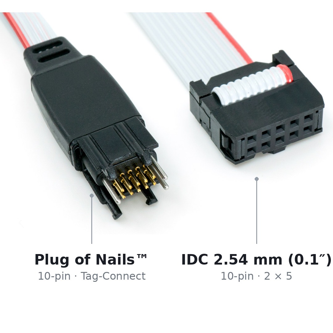 Both ends of the TC2050-IDC cable side by side: on the left the 10-pin Tag-Connect connector with spring pins and legs, on the right the 10-pin IDC connector on a 2.54 mm pitch.