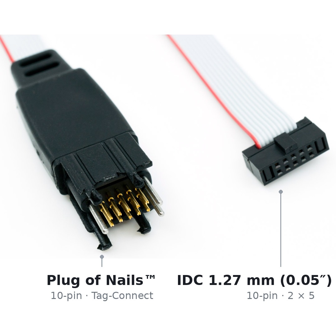 Beide Enden des Kabels TC2050-IDC-050-ALL nebeneinander: links der zehnpolige Tag-Connect-Stecker mit Federkontaktstiften und Legs, rechts der zehnpolige IDC-Stecker mit 1,27 mm Raster.